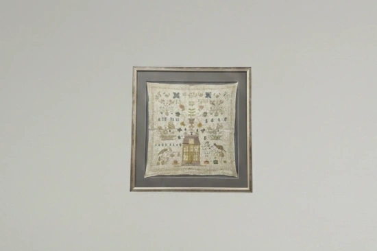 Antieke merklap in conserverende lijst